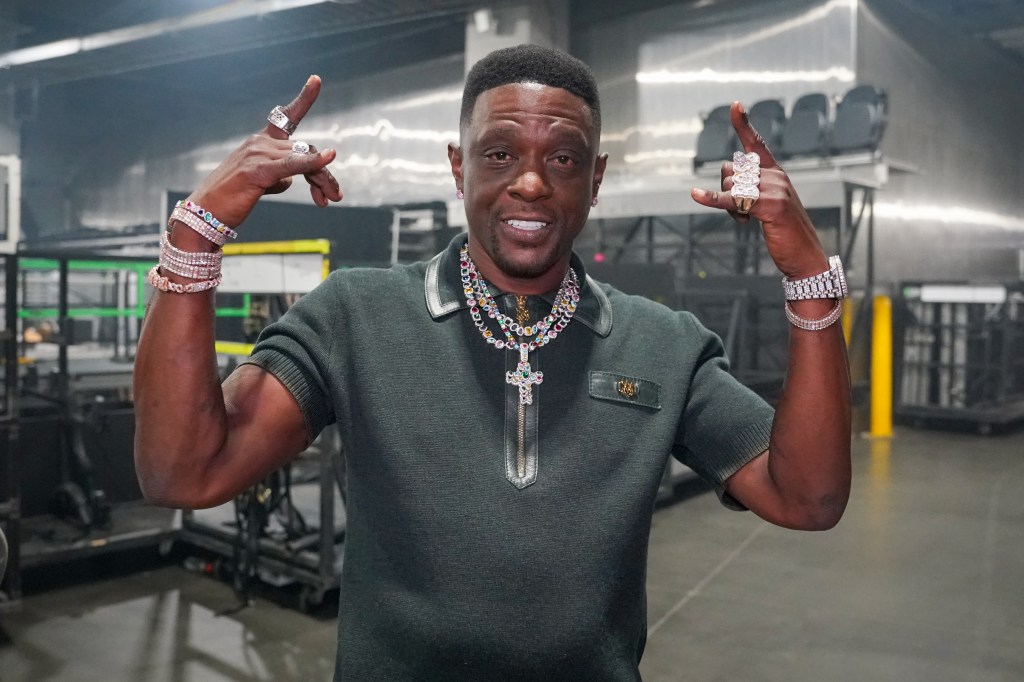 Boosie Badazz posing with hands raised, covered in diamond jewelry.