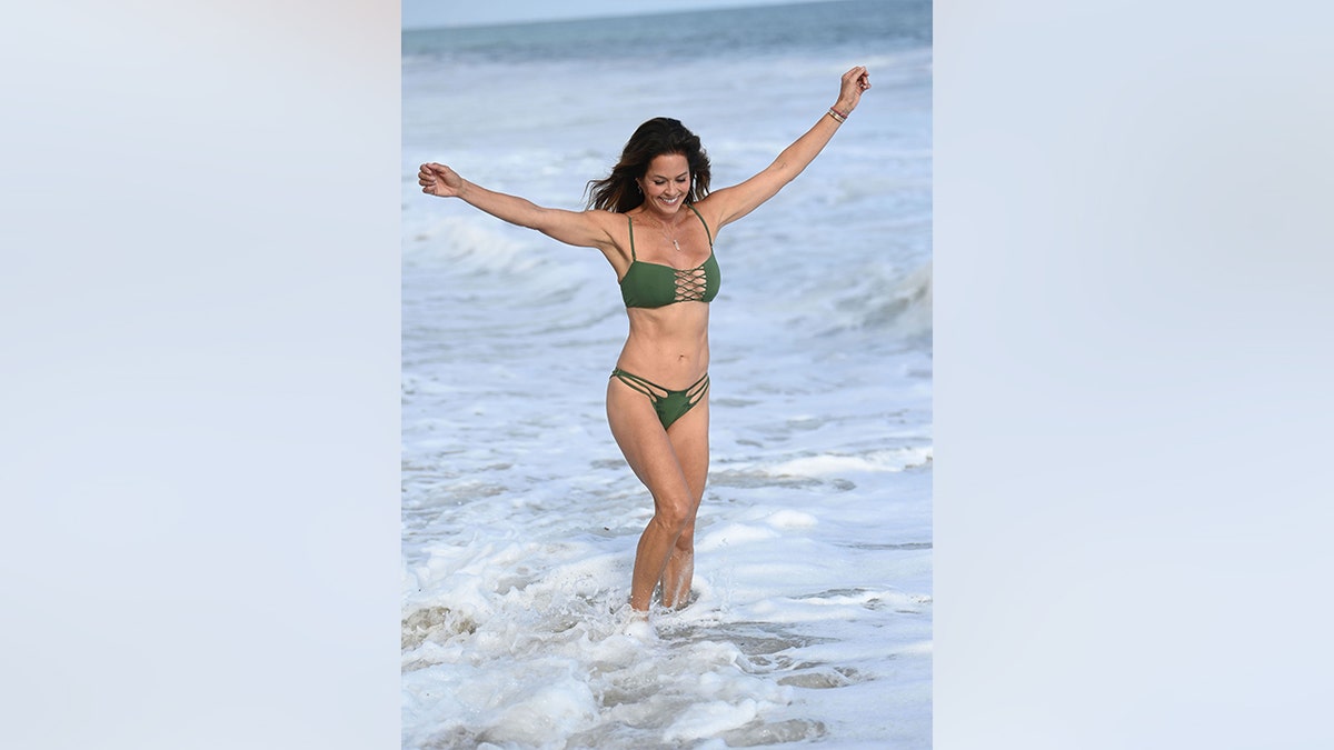 Brooke Burke in the ocean in Malibu in a green bikini.