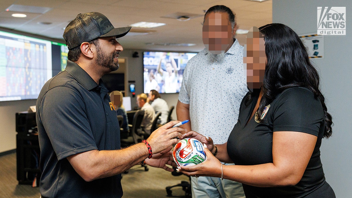 Kash Patel signs a soccer ball.