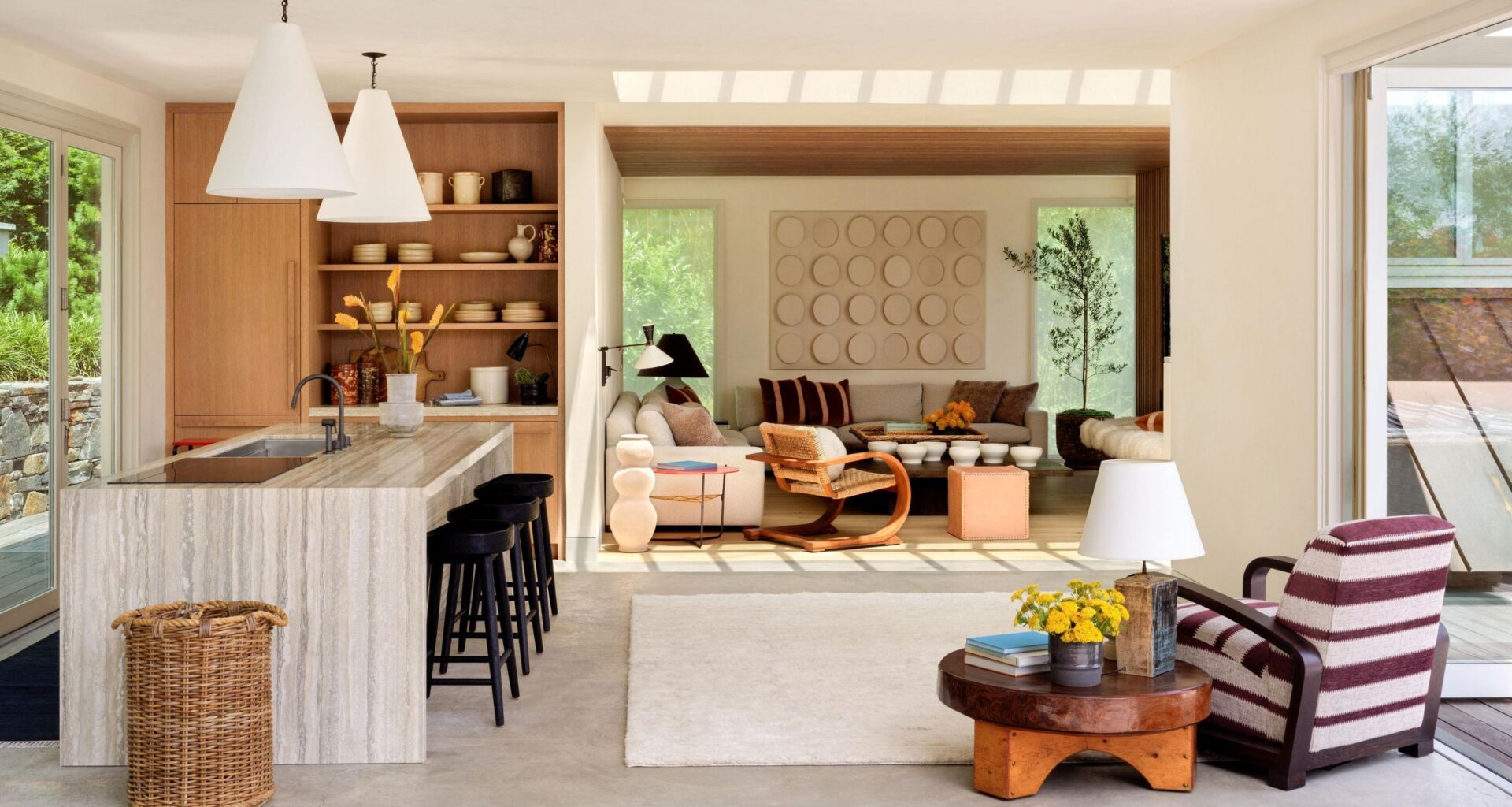 an open plan poolhouse with patio doors, a small oak and marble kitchen and layered striped and vintage wooden interiors