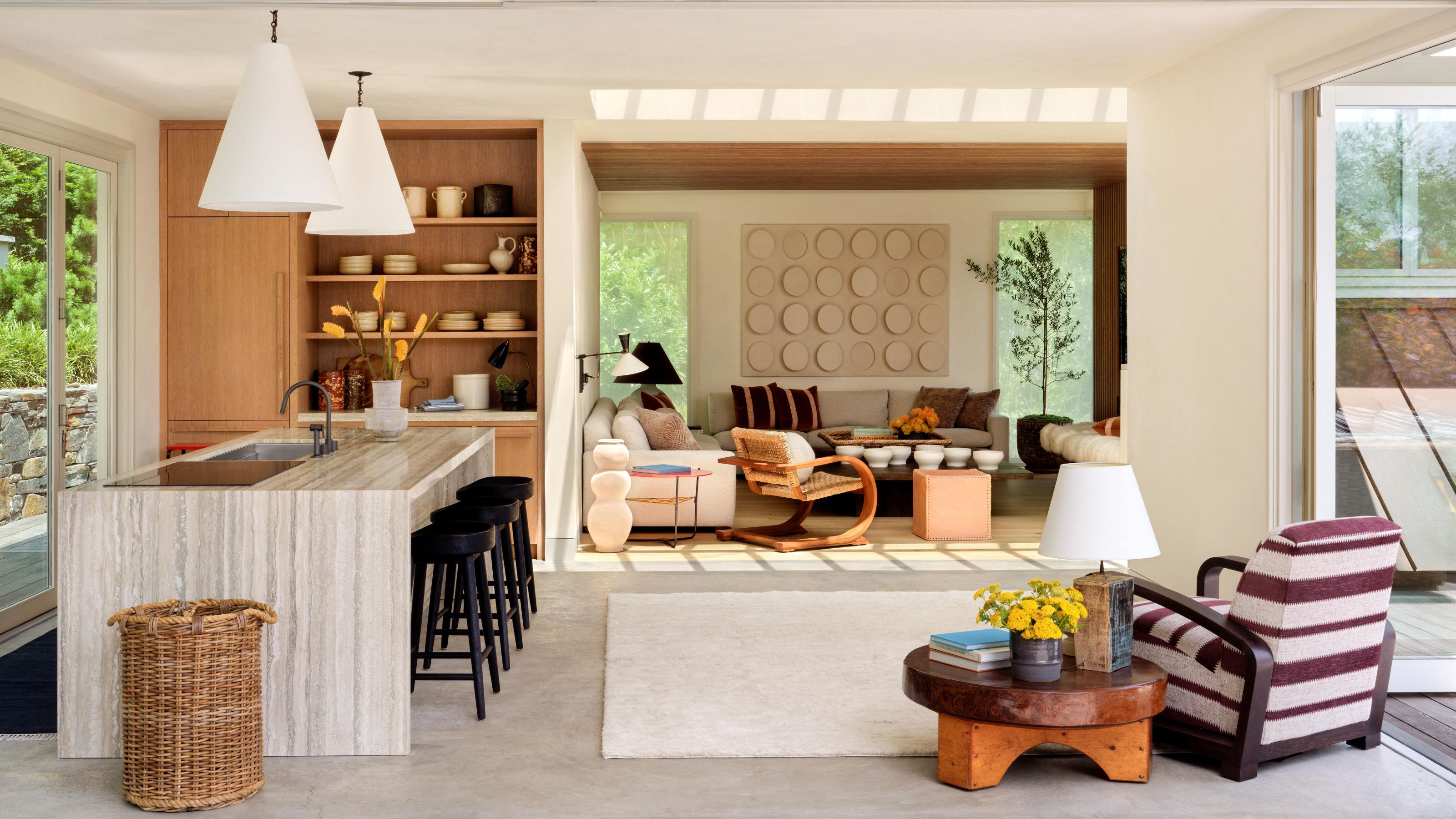 an open plan poolhouse with patio doors, a small oak and marble kitchen and layered striped and vintage wooden interiors