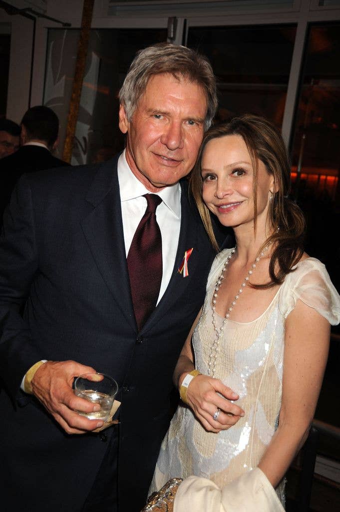 Harrison Ford holding a drink while standing next to wife Calista Flockhart as they smile for photo at a party in Hollywood in 2010