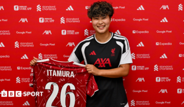 Mao Itamura holds up a Liverpool shirt bearing her surname and the number 26 on the back