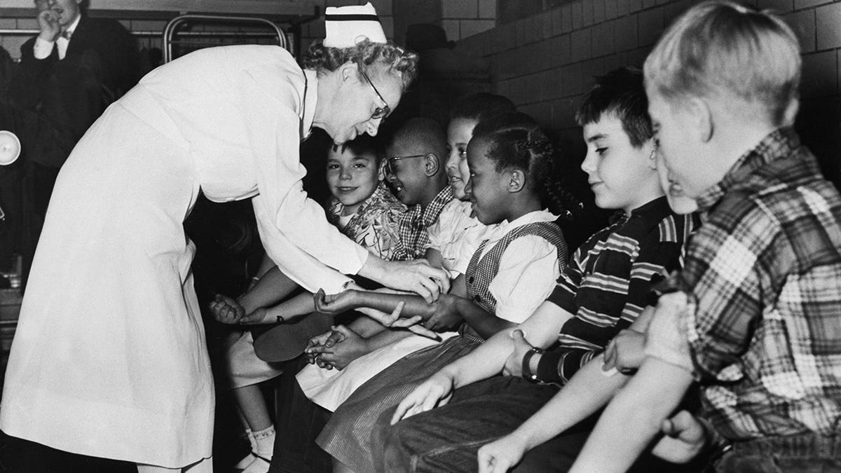 Nurse prepares children for a polio vaccine shot in a school setting.