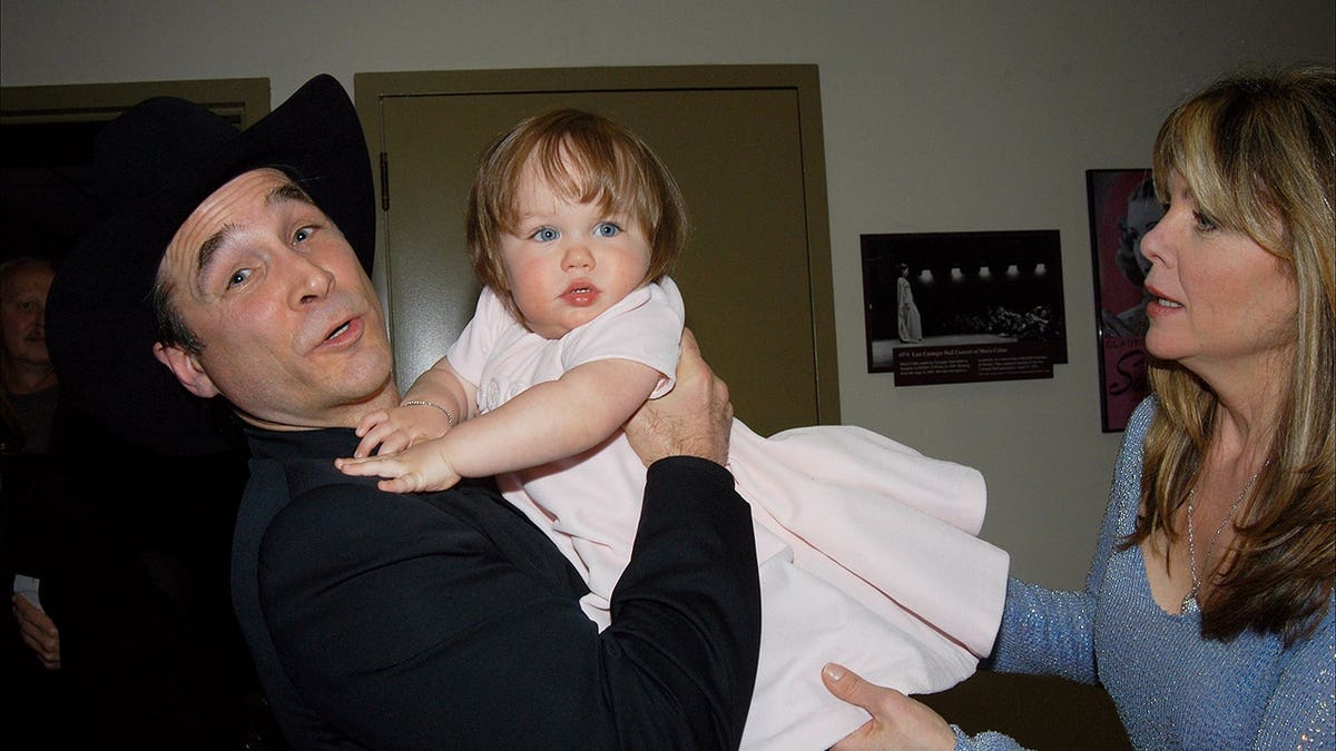Clint Black holding daughter Lily with wife Lisa Hartman Black backstage.
