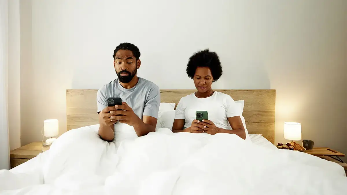 Couple in bed looking at their phones