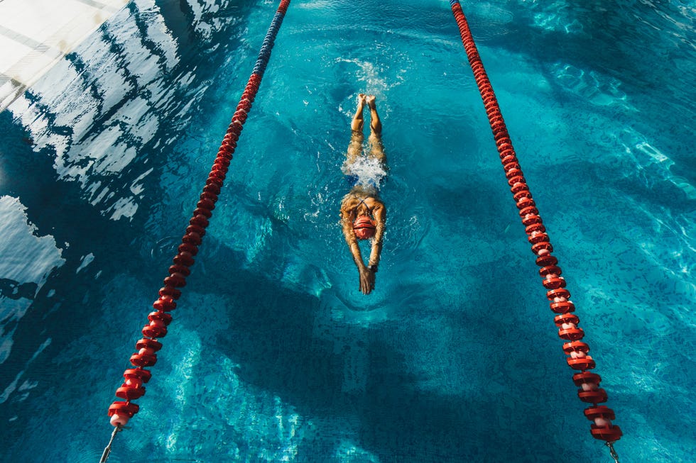 View from above of woman swimming by track in the pool. Sports concept, unrecognizable person. swimming workout in pool. clear and blue water surface. healthy lifestyle, sportive hobby. professional sportswoman. triathlon training.