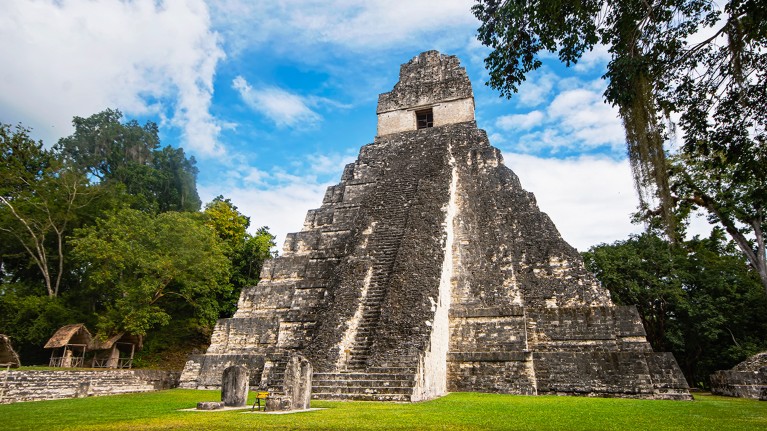 The well preserved Temple of the Great Jaguar in Tikal, Guatemala. The form is a distinctive pyramid shape with stepped design in a forest clearing.