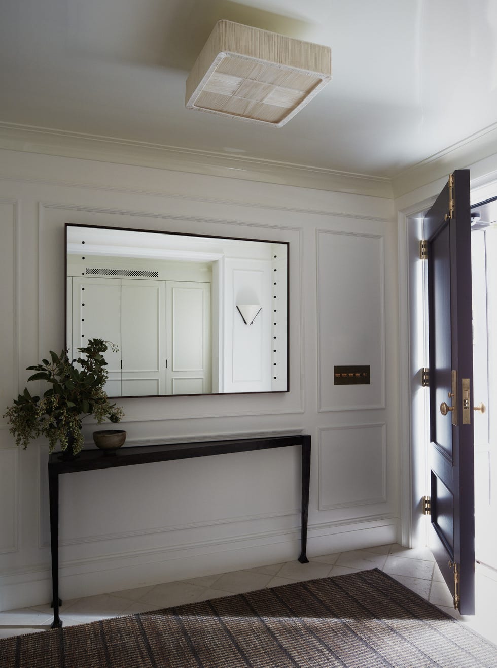 Elegant entryway featuring a dark console table, a large mirror, plants, and a stylish ceiling light.