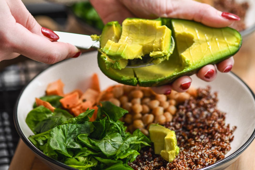 Avocado Half Being Removed From Peel With Spoon For Added Healthy Fats to Meal avocado half being removed from peel with spoon for added healthy fats to meal