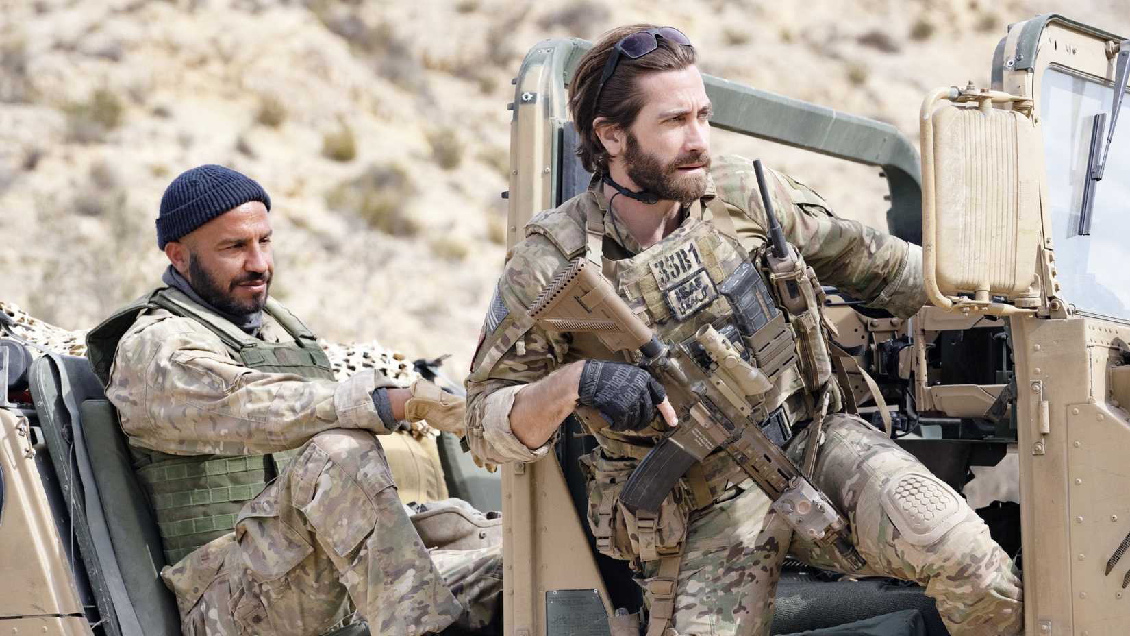 Dar Salim and Jake Gyllenhaal in The Covenant wearing military gear near a truck