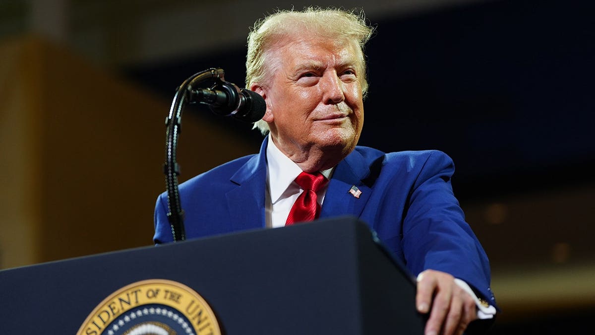 President Donald Trump speaks at a podium at Wheeler High School.