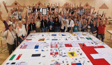 The group surrounding their embroidery and celebrating with GWR Adjudicator and certificate