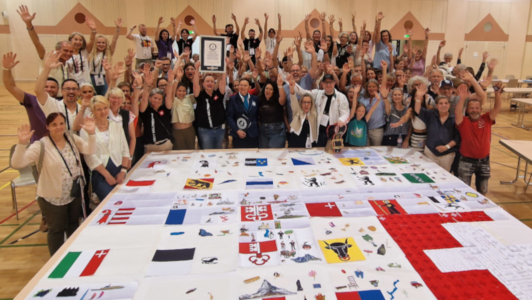 The group surrounding their embroidery and celebrating with GWR Adjudicator and certificate