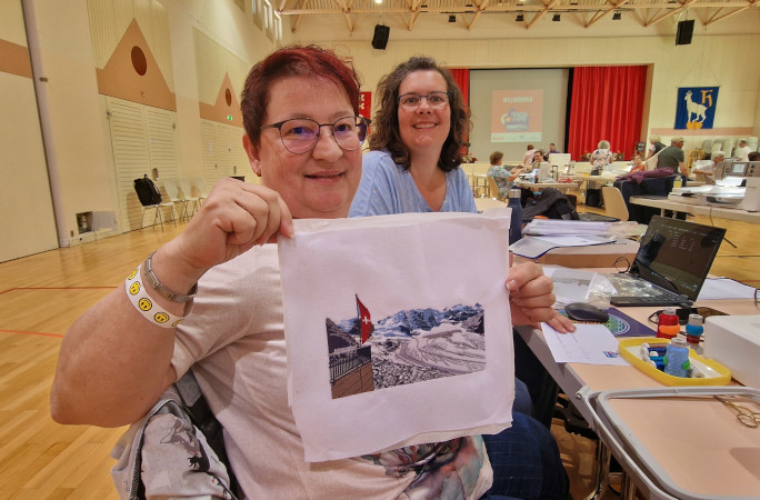 A volunteer holding up her embroidered nature scene