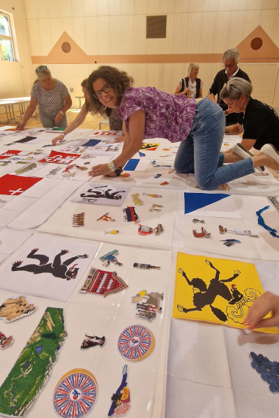 A woman sitting on the table arranging the embroidery squares