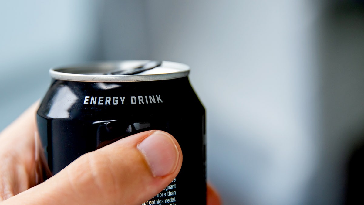 A hand holds an energy drink.