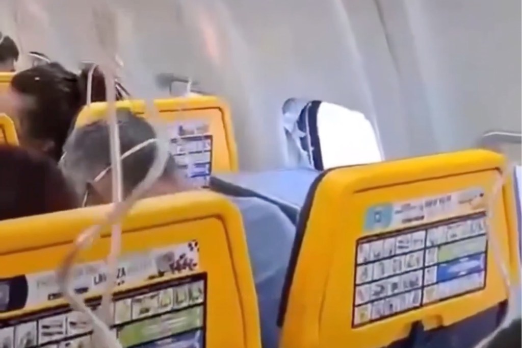 Airplane cabin with a shattered window, exposing the turbulent air outside.