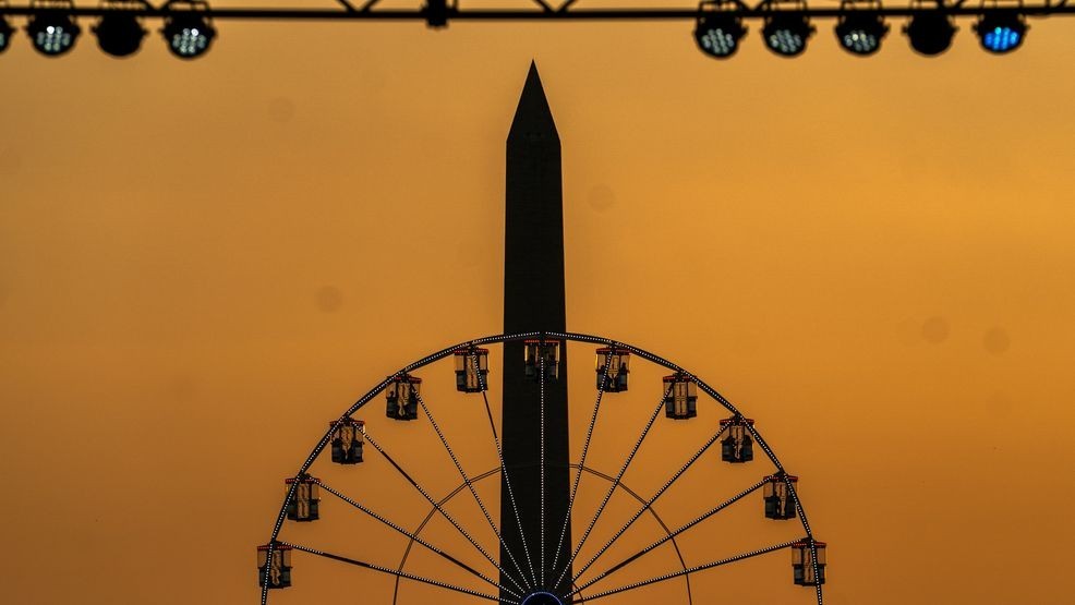 The Washington Monument and the ferris wheel on the National Mall are seen at sunset, Wednesday, July 1, 2026, on the National Mall in Washington. (AP Photo/Allison Robbert)