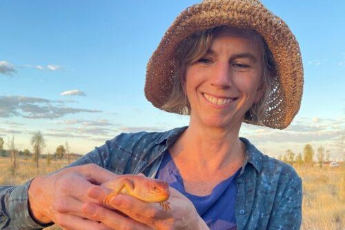 A woman holding a lizard.