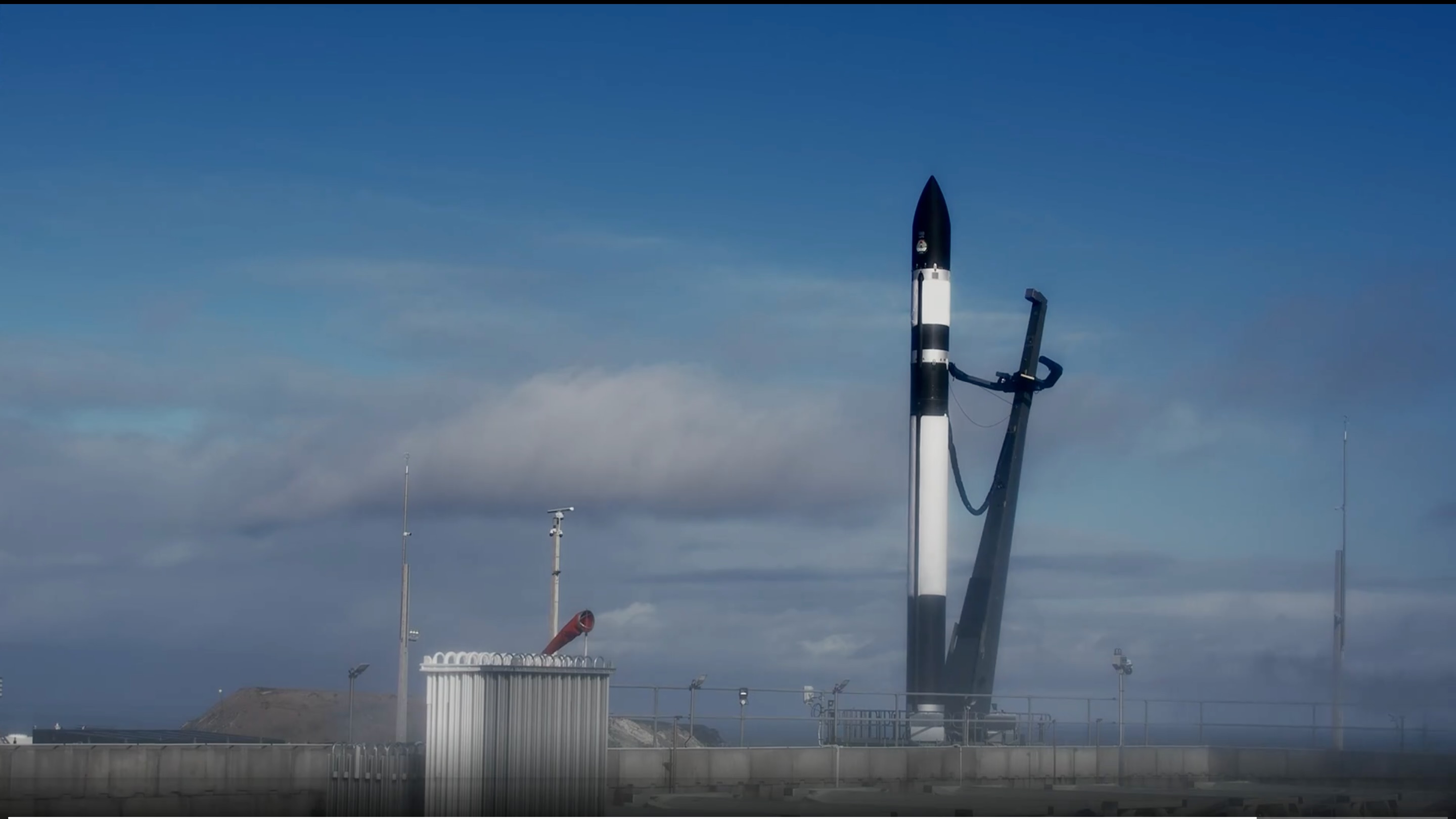 a black and white rocket stands on a launch pad beneath a blue sky