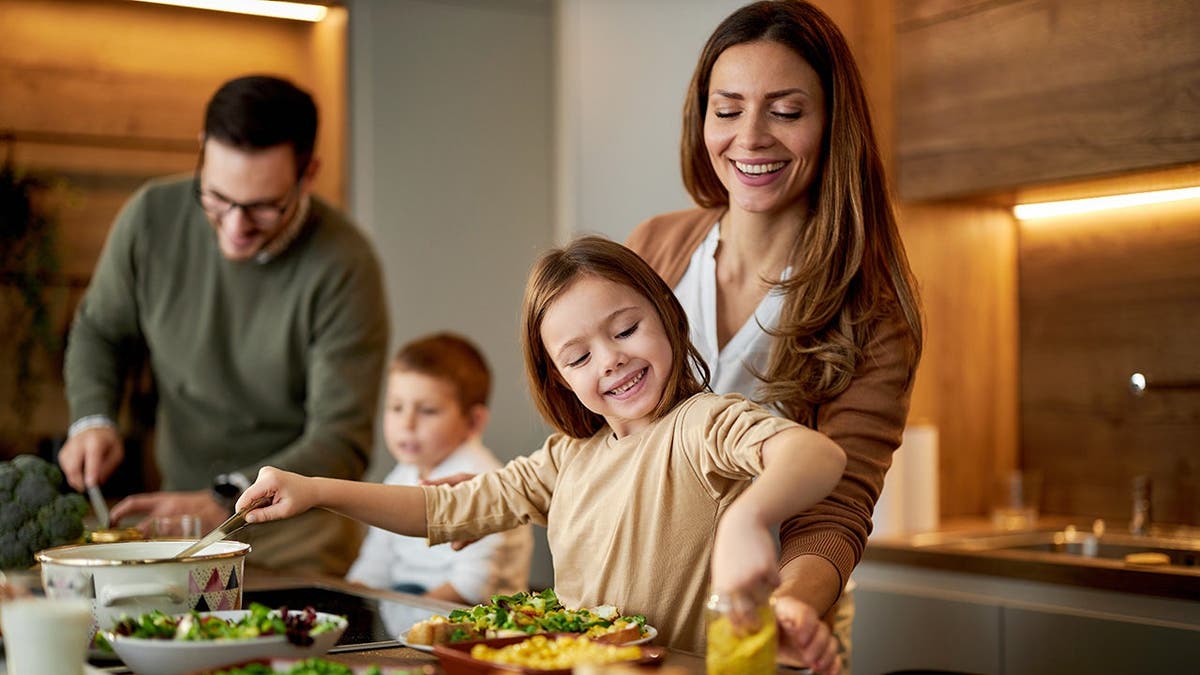 A family prepares a meal together in a kitchen.
