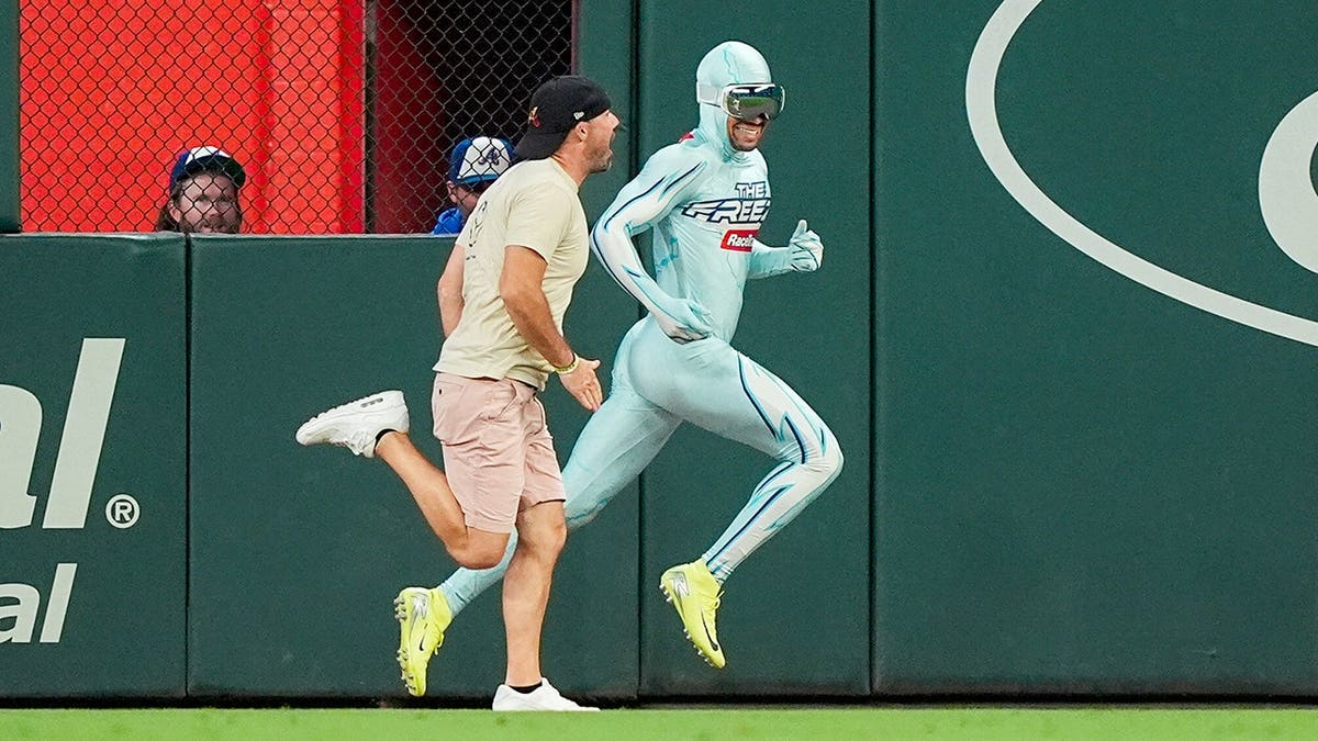 A fan races The Freeze on the field between innings at Truist Park.