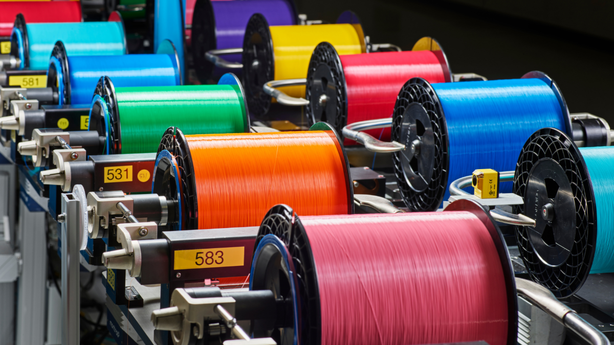 Spools of fiber optic cables are seen on a factory belt.