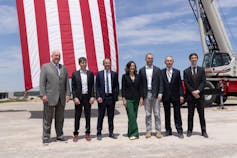 A group of people stand together on a piece of bare ground.