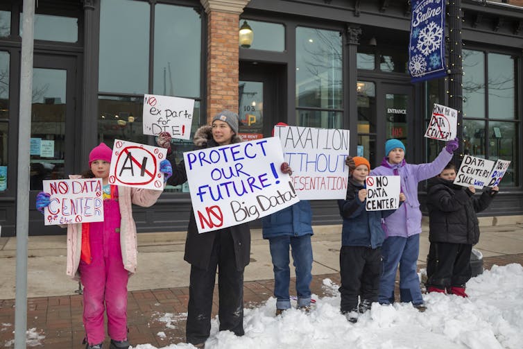 People bundled up against winter cold hold signs saying 'No data center' and 'Protect our future - no big data.'
