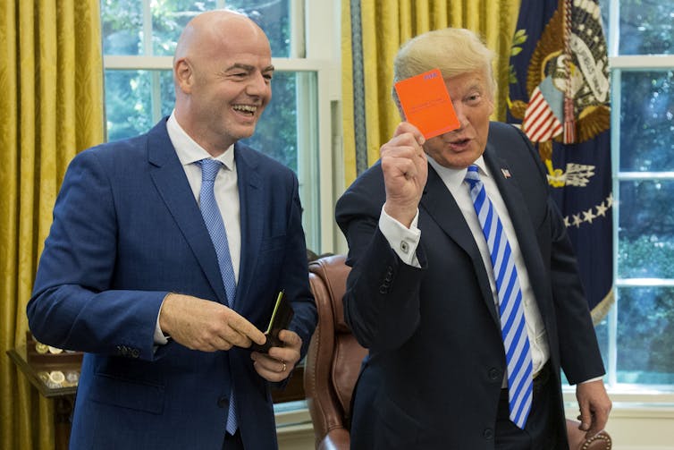 US President Donald Trump holds up a red card, standing next to FIFA President Gianni Infantino, in 2018.