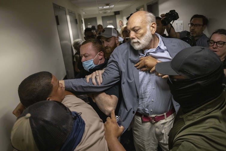 A group of people struggling with ICE officers at a court house.