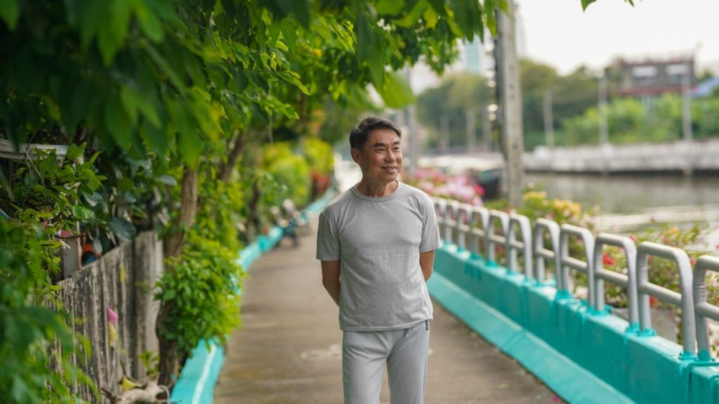 older Asian man taking a walk through a park