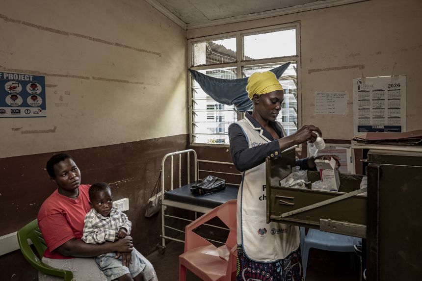 A mentor working as part of a program to prevent mother-to-child HIV transmission sits with a mother and her son at Migosi Sub-county Hospital in Kisumu, Kenya, in April 2025 – part of a wide range of work to combat HIV/AIDS that is supported by CDC.