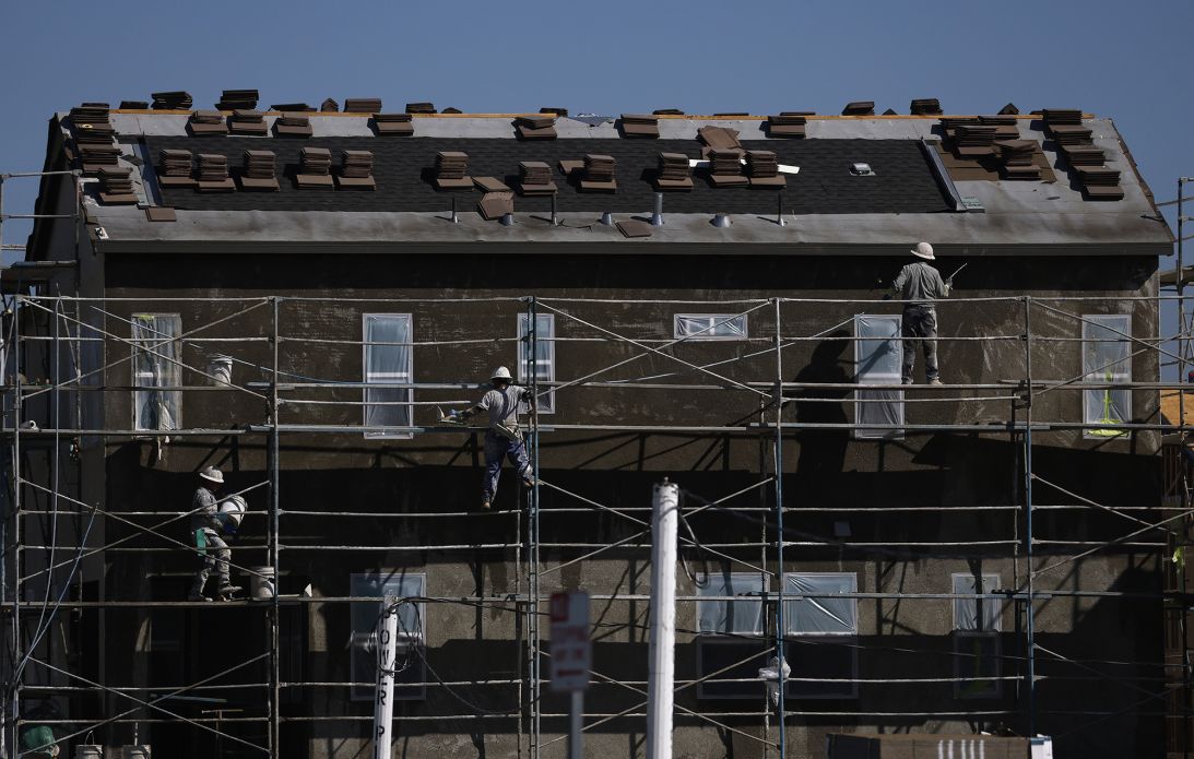 Construction workers stand on scaffolding as they work on a home under construction at a new housing development on June 24, 2026 in Valencia, California.