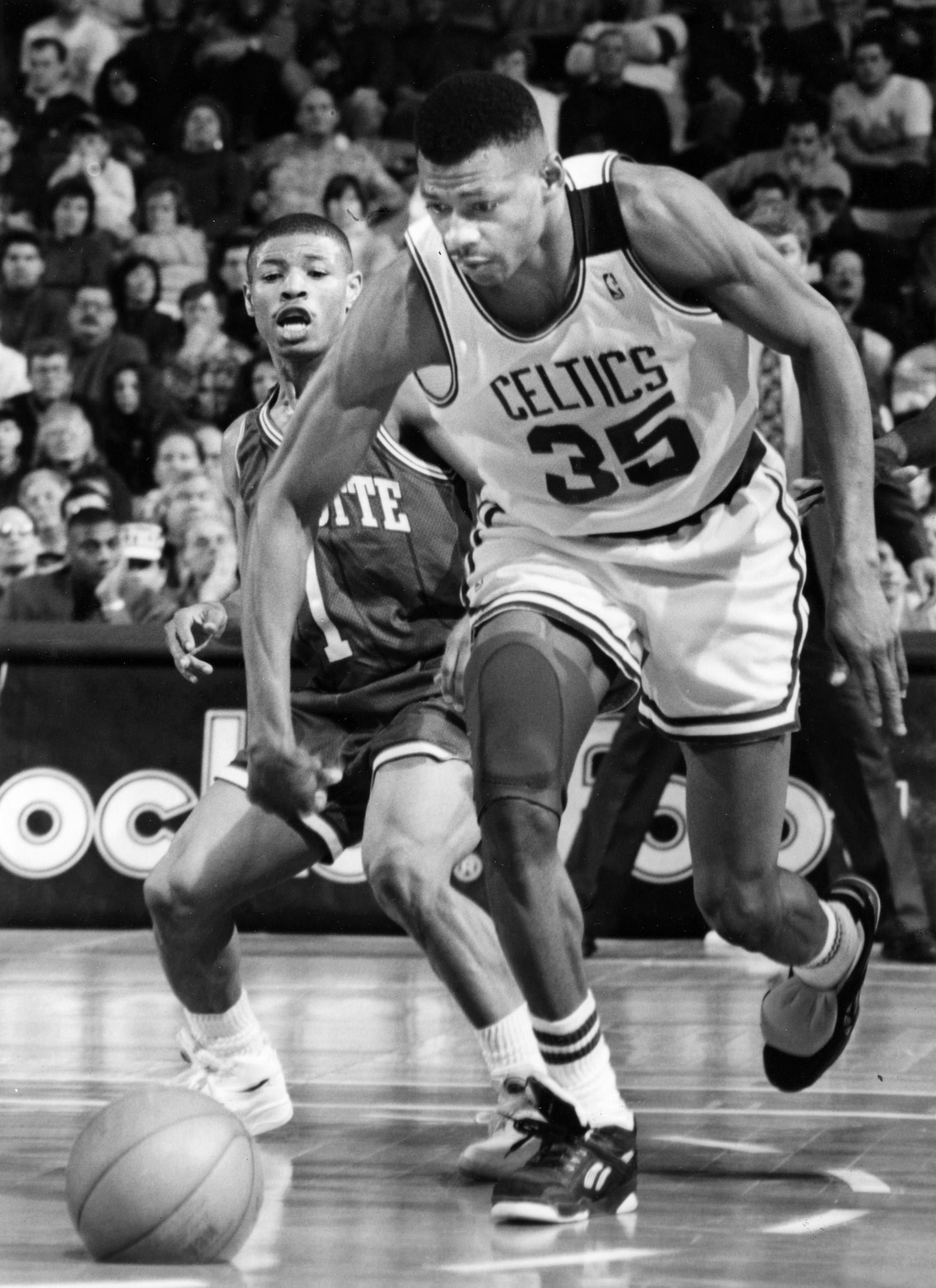 BOSTON, MA - MARCH 14: Boston Celtics Reggie Lewis, right, and Charlotte Hornets Muggsy Bogues, left, scramble for the ball during a game at the Boston Garden, March 14, 1993. (Photo by Pat Greenhouse/The Boston Globe via Getty Images)