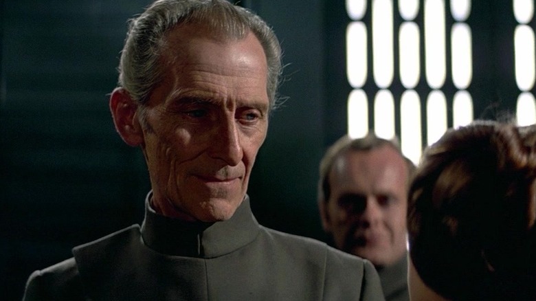 Peter Cushing as Grand Moff Tarkin smiling down at Princess Leia in Star Wars: A New Hope.