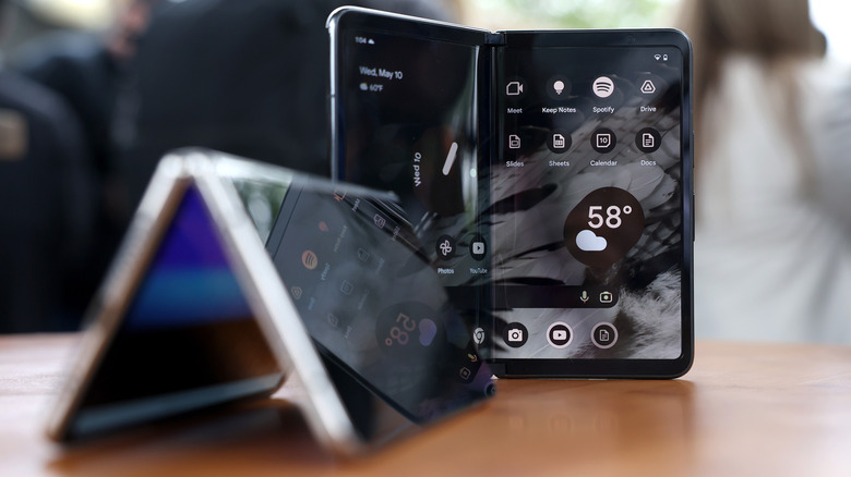 Two foldable phones on a brown surface.