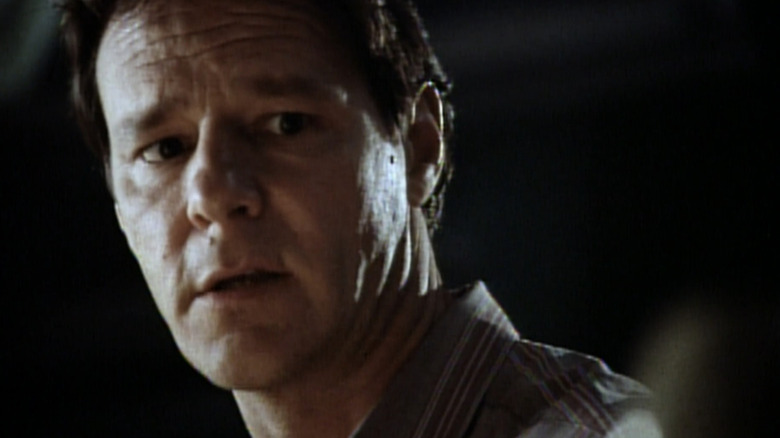 Chris Mulkey's Bram Walker looks across frame against a black background in Ghost in the Machine