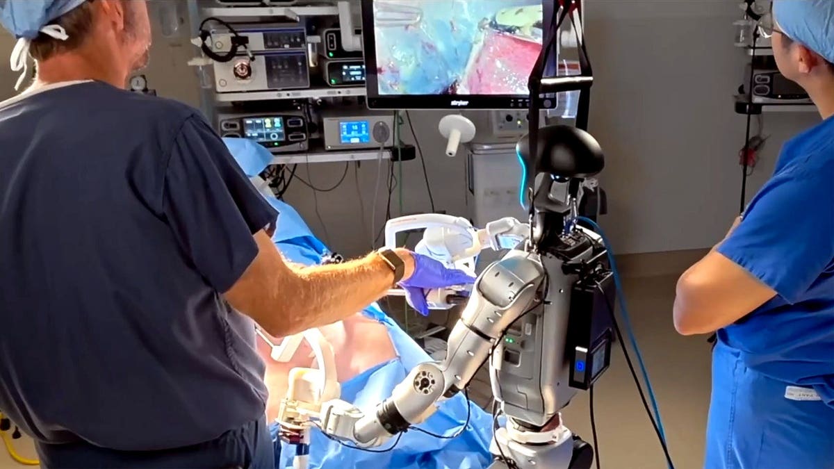 A humanoid robot is assisted by medical professionals during a surgery.