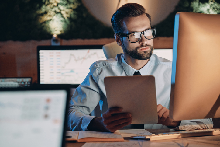 A man researching whether to invest in the S&P 500 or Dow Jones.