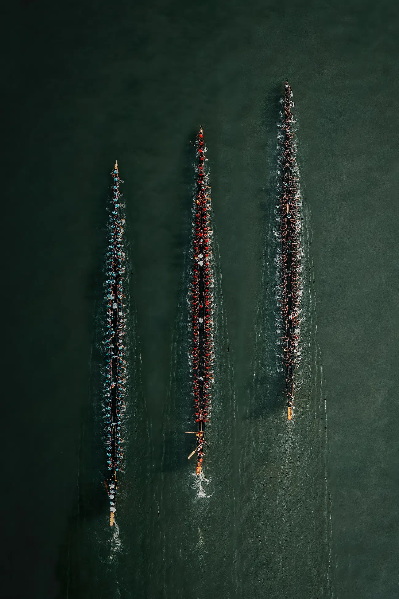 Savadmon Avalachamveettil, Ireland. Rhythm of the Oars. From above the Nehru Trophy Boat Race at Punnamada Lake, three snake boats glide in perfect rhythm. Oars strike in unison, turning human effort into pattern - where tradition, teamwork, and motion merge into a single, powerful flow.