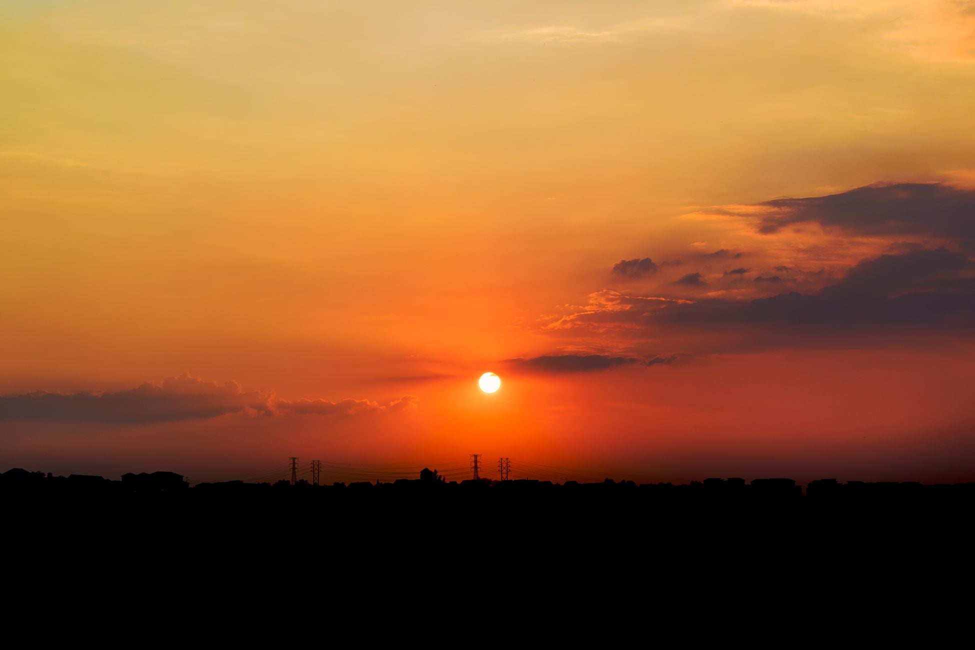 Stunning sunset view with vibrant orange and yellow hues over a silhouetted city skyline.
