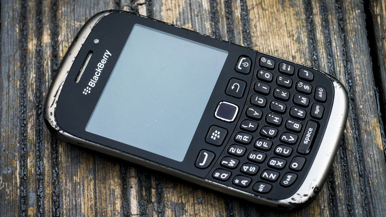 A BlackBerry phone lays on a woodgrain surface
