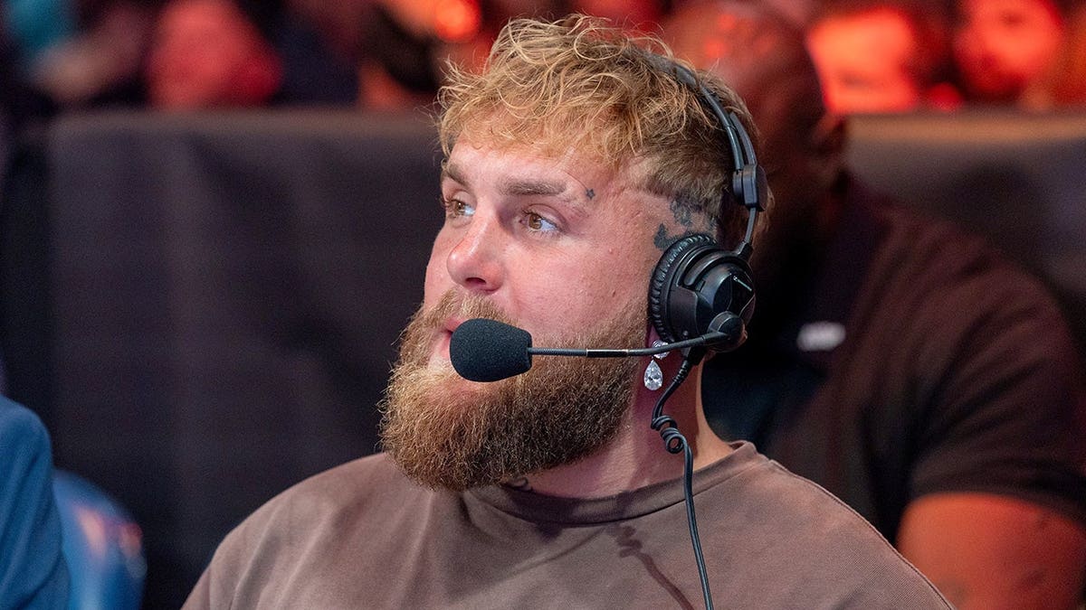 Jake Paul watches bouts from ringside during a boxing event.