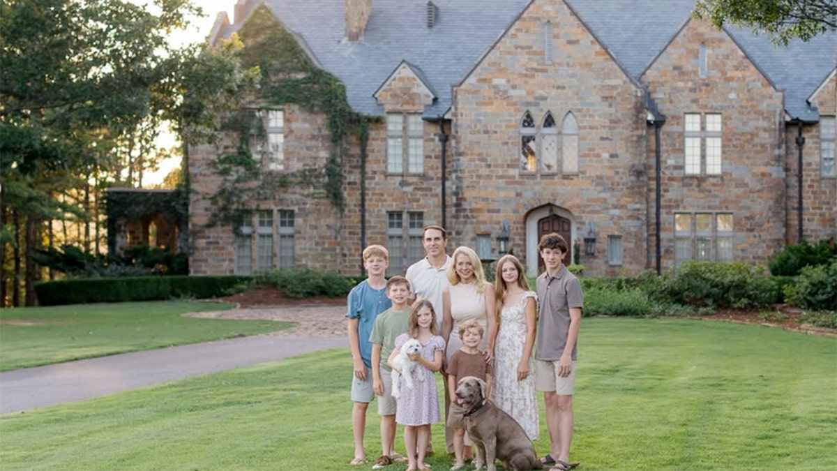 Jennifer Maune, her husband, three sons, two daughters and two dogs pose for a photograph outside their Arkansas house.