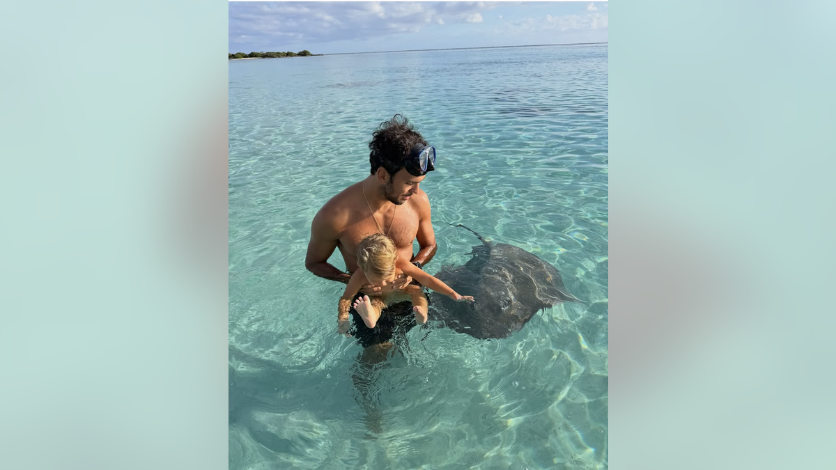 Joaquim Valente holds his son in the ocean
