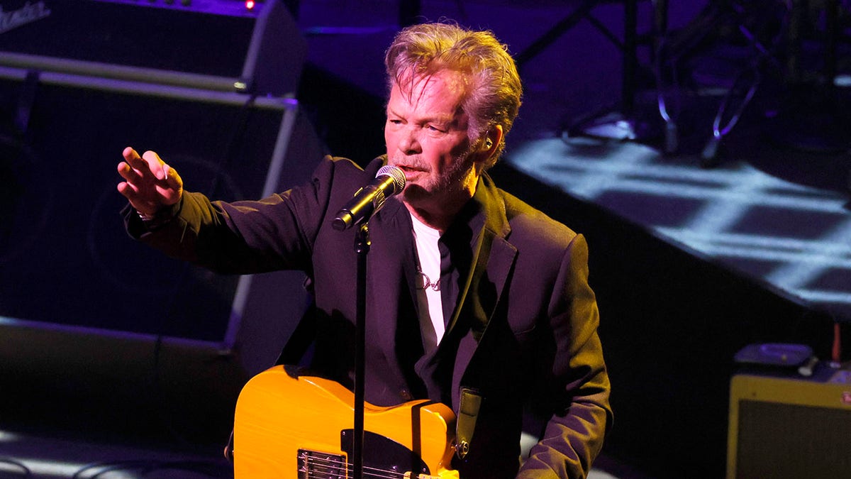 John Mellencamp holding a guitar and speaking