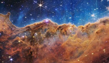 Colorful nebula with bright stars scattered across a vivid blue and orange cosmic cloud, resembling a mountainous landscape in outer space.