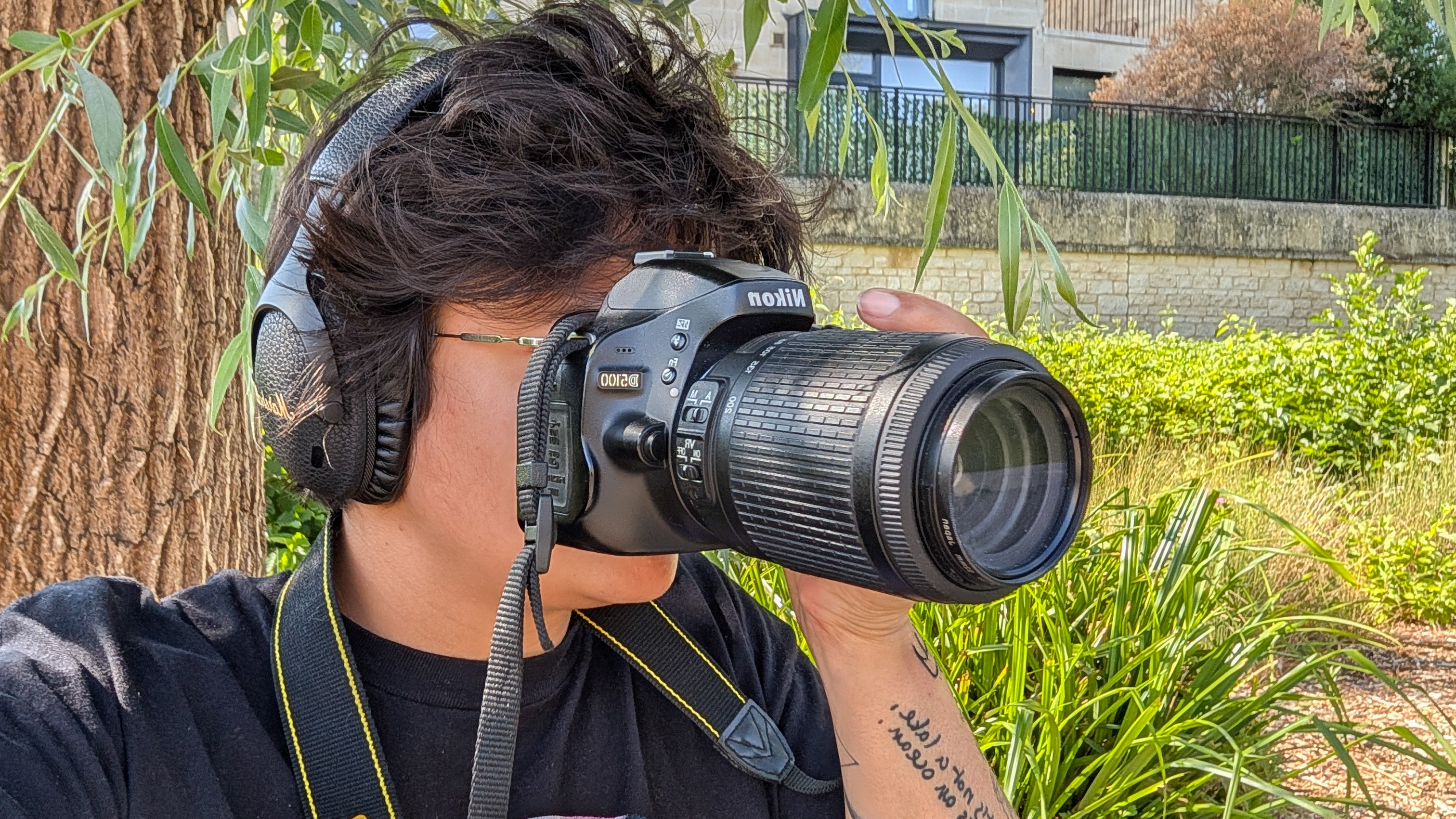 A person holding a Nikon D5100 DSLR camera